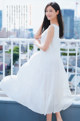 A woman in a white dress standing on a balcony.