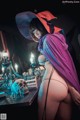 A woman dressed as a witch sitting at a table.