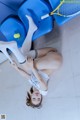 A woman laying on the floor with a tennis racket and ball.