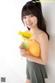 A woman in a yellow top holding a yellow flower.