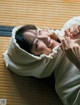 A woman laying on the floor with a toothbrush in her mouth.