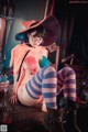 A woman in a witch costume sitting on a table.