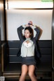 A woman in a skirt and blazer sitting on a bench.