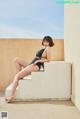 A woman in a black bathing suit sitting on a ledge.