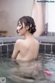 A woman in a bathtub with a flower in her hair.