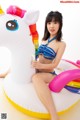 A woman in a bikini sitting on an inflatable unicorn.