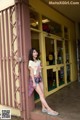 A woman standing in front of a store with her legs crossed.