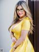 A woman in a yellow dress and glasses posing for a picture.