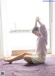 A woman sitting on a purple rug in front of a window.