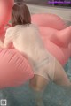 A woman in a white shirt is sitting on an inflatable pool float.