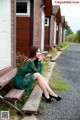 A woman in a green dress sitting on a bench.